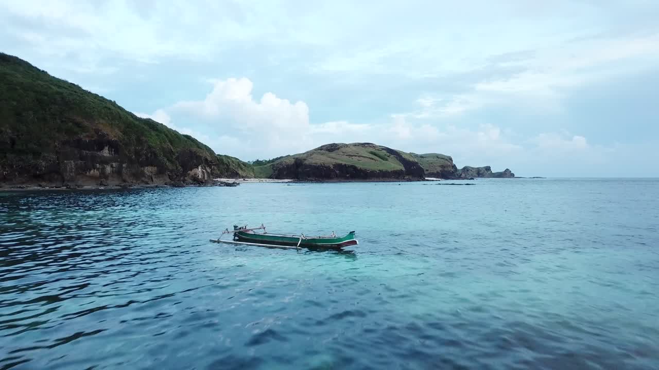 barco solitario aéreo 4k flotando en el paso elevado de aguas azules, indonesia
