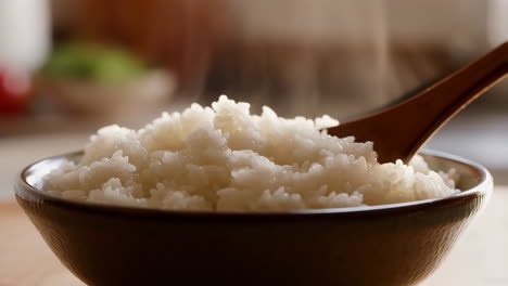 steaming white rice in a bowl with a wooden spoon