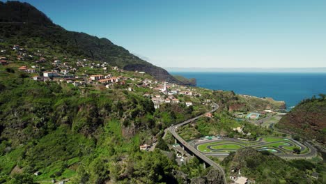 drone footage of madeira village landsacpe, curvy road and ocean in the background