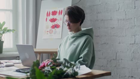 woman working on a laptop in her art studio