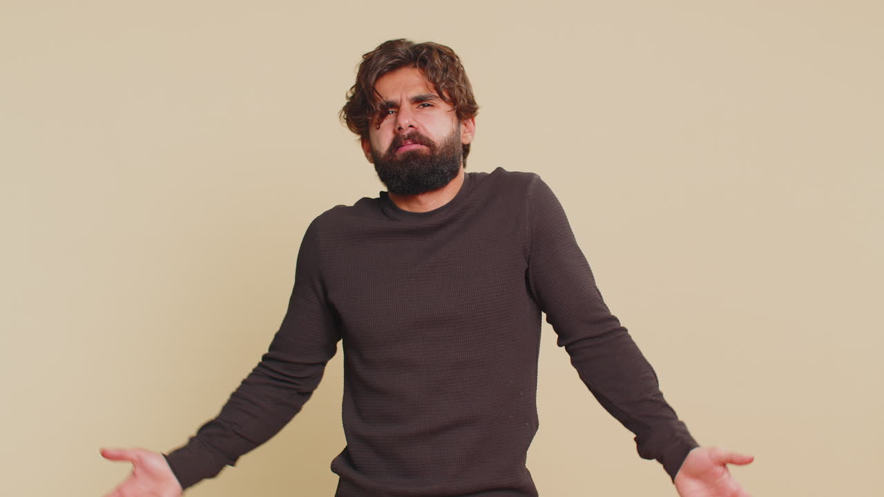 Indian young man showing bla blah nonsense gossip gesture with hands against beige background