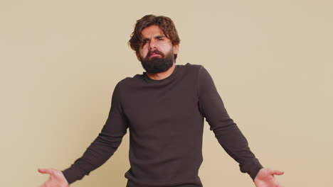 indian young man showing bla blah nonsense gossip gesture with hands against beige background