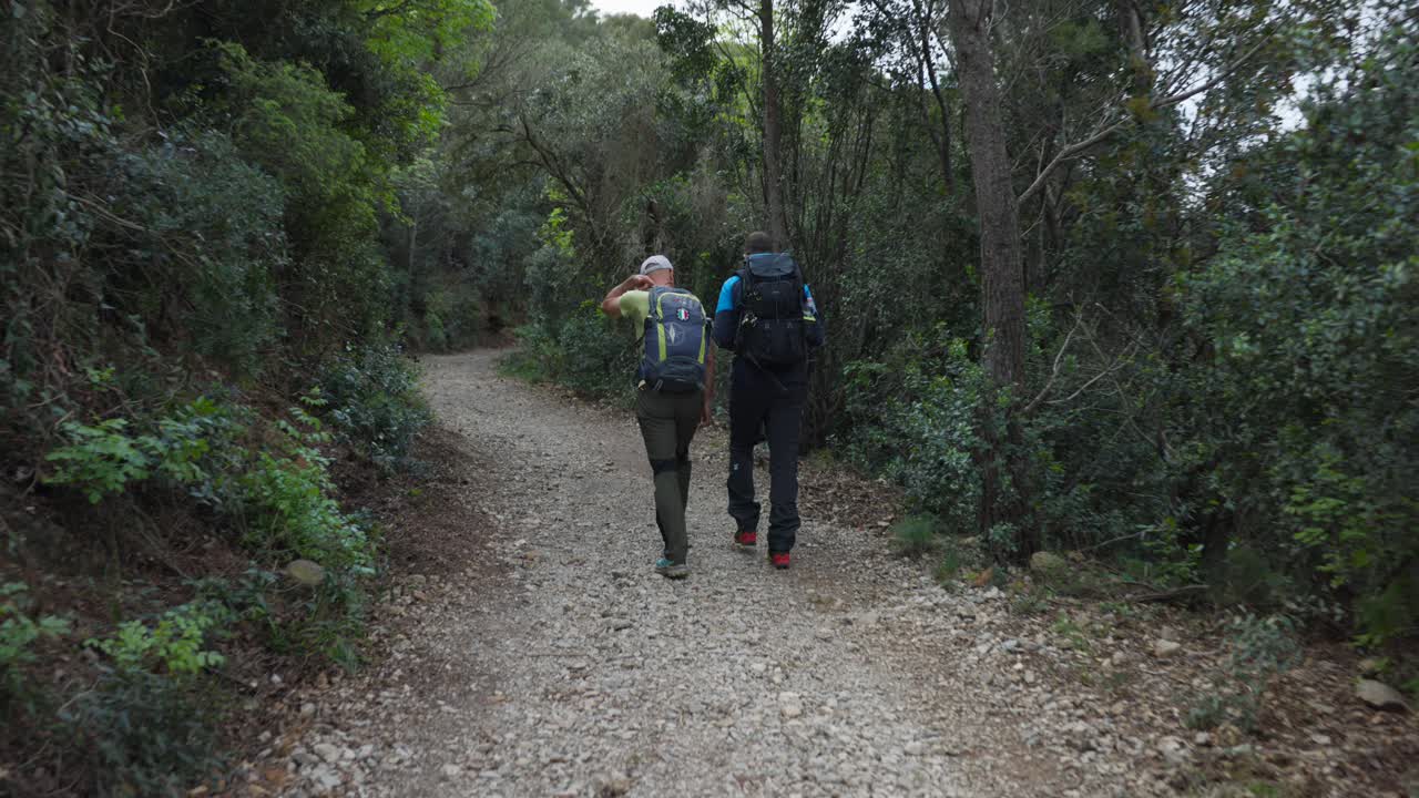 Two Men With Backpacks Traveling Over Mountain Trails In Noli, Italy. Static Shot