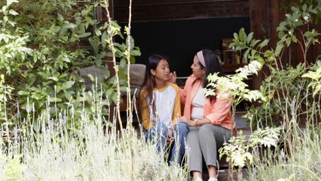 multiracial grandmother and young woman sitting on porch, sharing heartfelt conversation outdoors