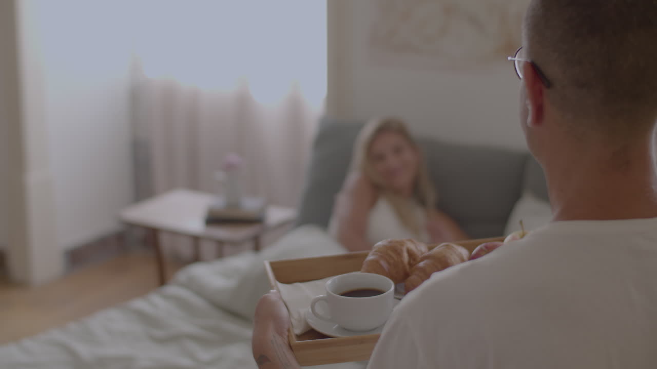 муж приносит завтрак в постель своей жены.