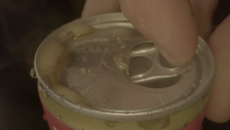 toma macro de la tapa de la lata de refresco que se abre a cámara lenta y derrama cola