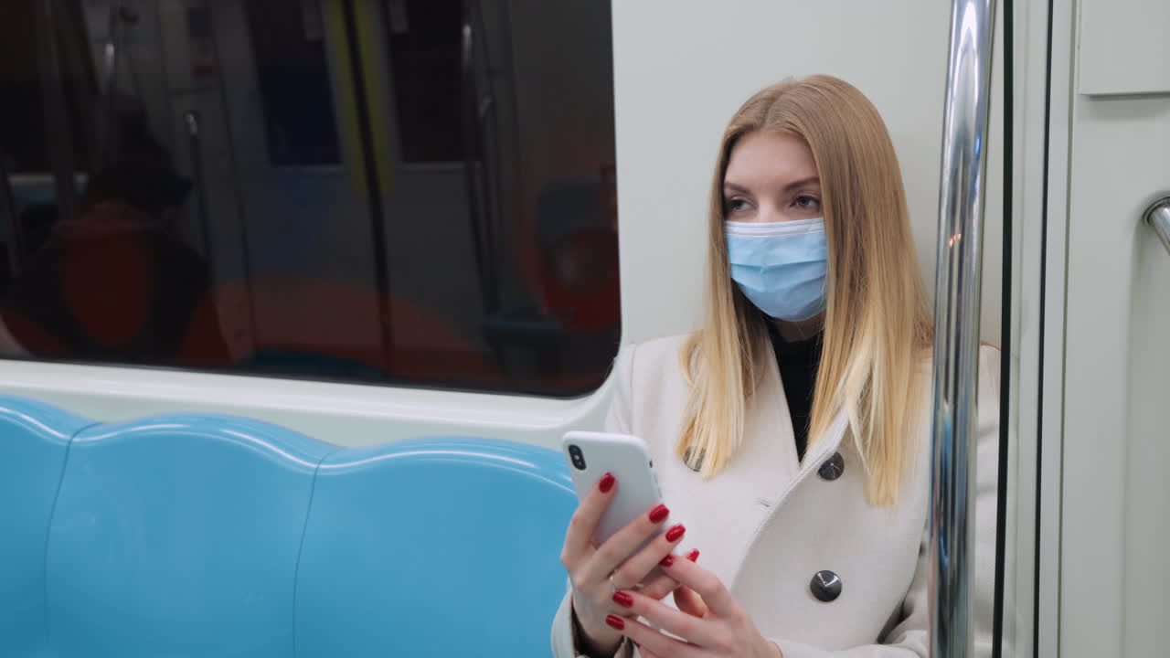 Woman using phone in subway wearing mask