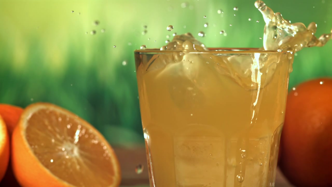 Ice Cube Splashing into a Glass of Orange Juice in Slow Motion