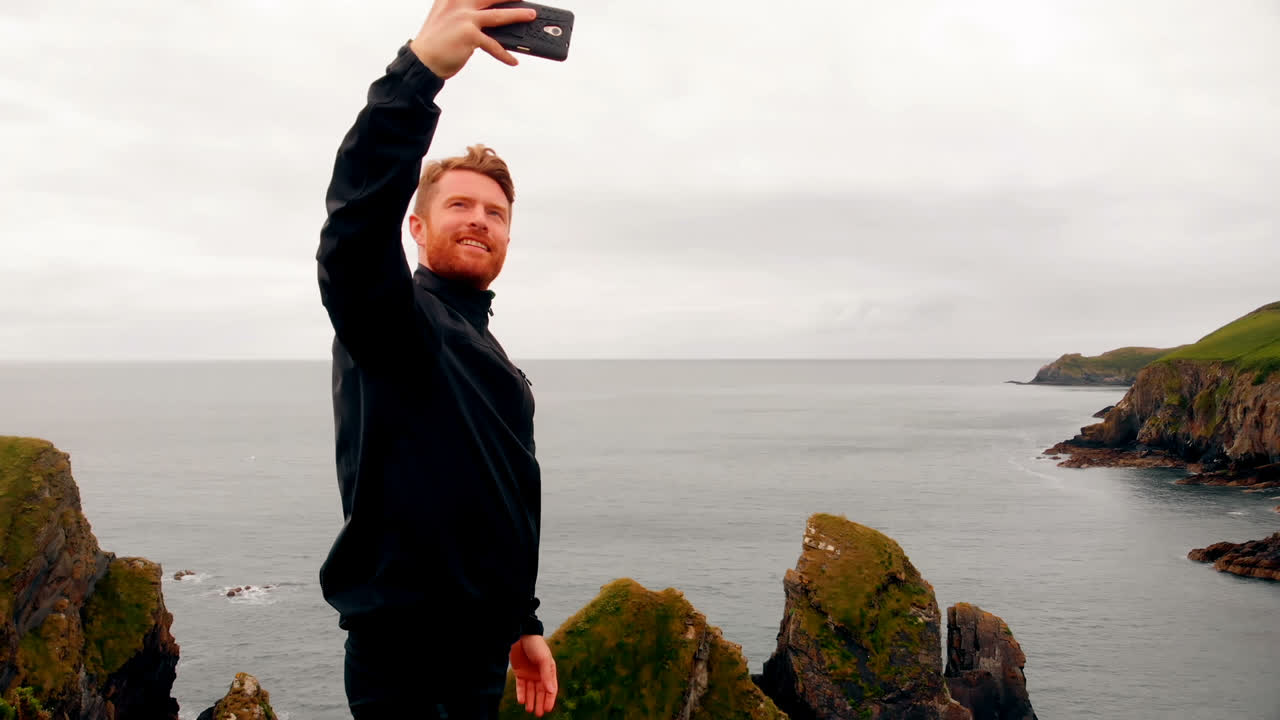 hombre tomando selfie desde el teléfono móvil en el acantilado 4k
