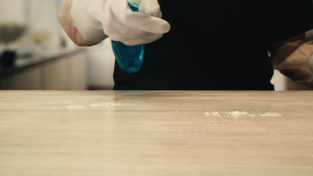 Hands in Gloves Spraying and Wiping a Wooden Surface