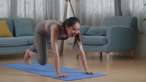 joven atleta asiática en ropa deportiva haciendo ejercicios de cardio rodillas altas y ejercicios de fortalecimiento del núcleo durante el entrenamiento en la alfombra en casa