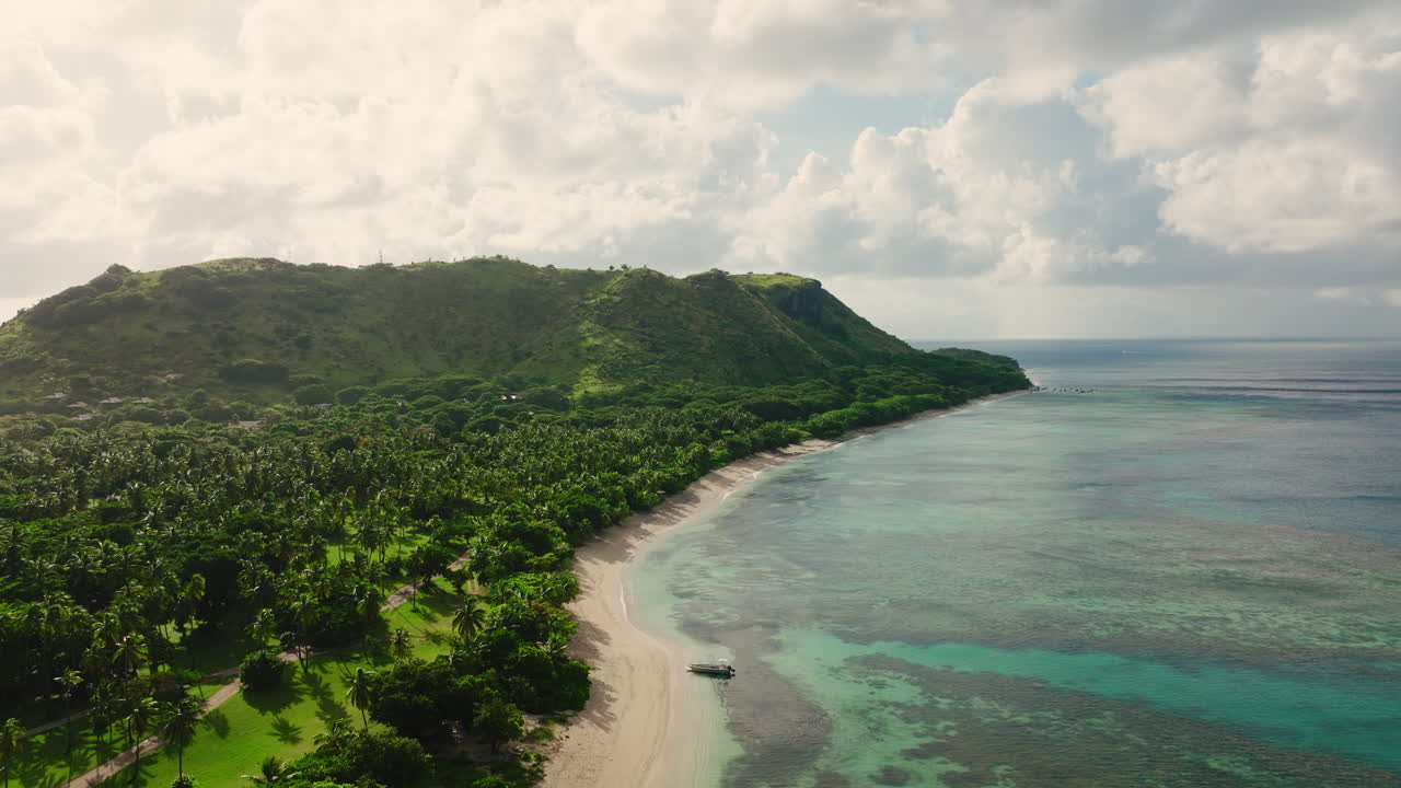 Overcast tropical beach and calm water with lush coastal forest in Fiji