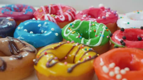 en una caja blanca se colocan hermosas y exuberantes rosquillas de forma redonda y esmaltes multicolores, bañadas con diferentes chocolates y salpicaduras de colores. dulces de primer plano. concepto de obesidad