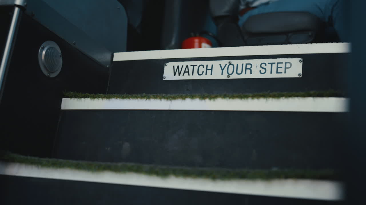 Closeup schoolbus entrance stairs with plate. Sign warn to watch your step.