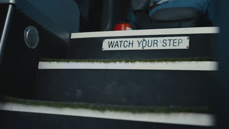 closeup schoolbus entrance stairs with plate. sign warn to watch your step.