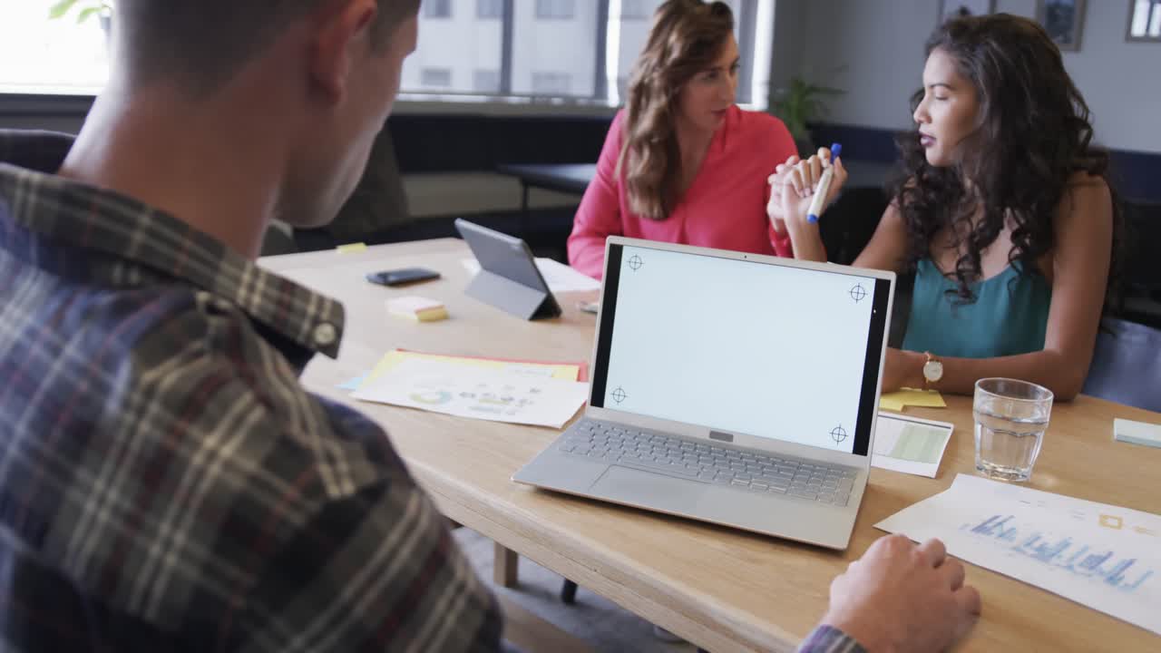 portátil con espacio de copia en la pantalla y diversos colegas en discusión en la oficina casual, cámara lenta