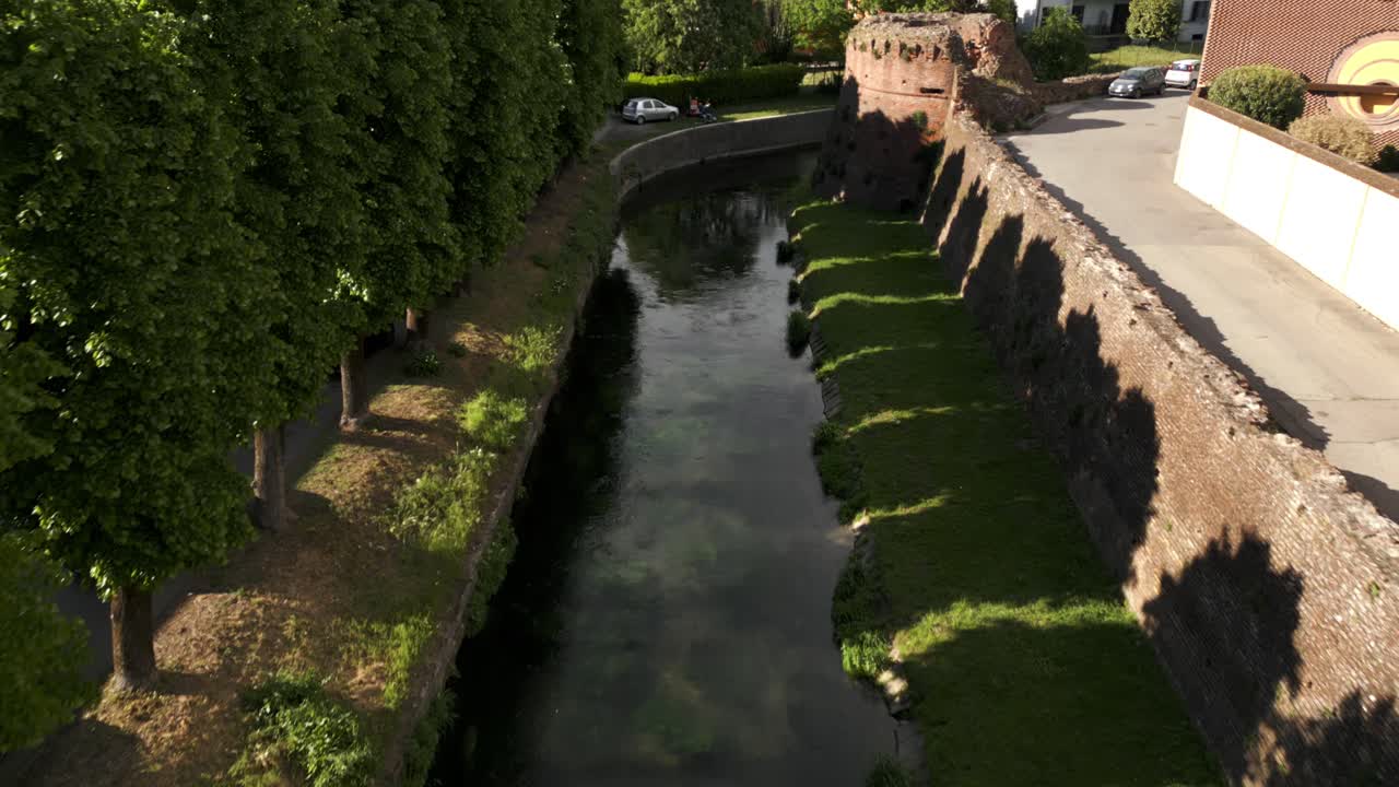 volando sobre el agua del canal a lo largo de la pared de bastioni balestrieri en soncino, italia