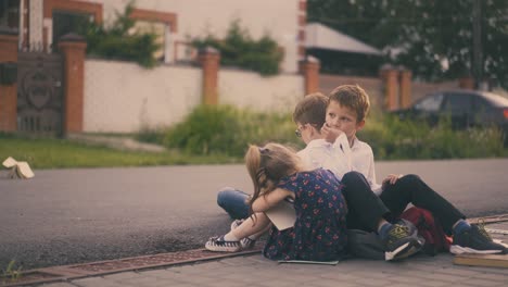 boy throws book doing home task with friends on pavement