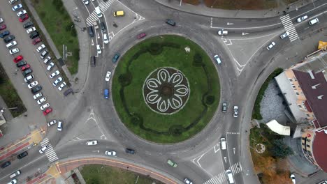 4k aerial view of roundabout road with circular cars in small european city at cloudy autumn day