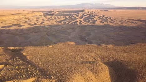 Eine-Dolly-Antenne-Einer-Wunderschönen-Steinwüste-Bei-Sonnenuntergang-Mit-Sandkräuselungen-Und-Harten-Schatten