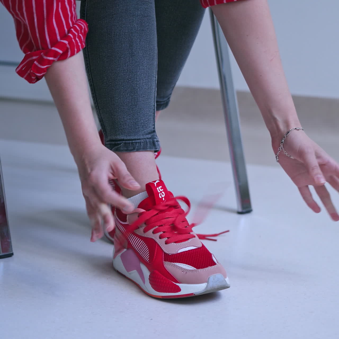 Woman tries to tie shoelaces on sneakers. Young woman feels pain in hands. Problems with hand joints. Close-up.