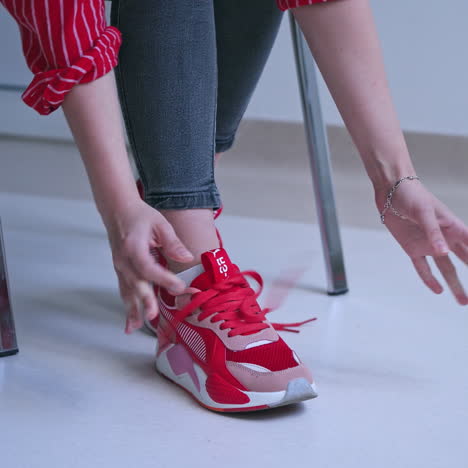 woman tries to tie shoelaces on sneakers. young woman feels pain in hands. problems with hand joints. close-up.