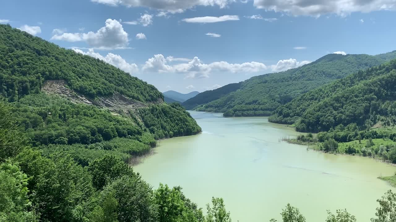 A blue lake in between two mountains surrounded by green trees and nature.