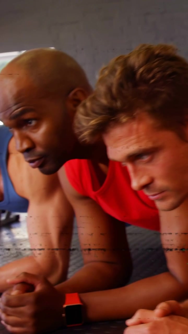 Vertical video: Man moving into forearm plank as glitches clearing, fitness group joining on mat