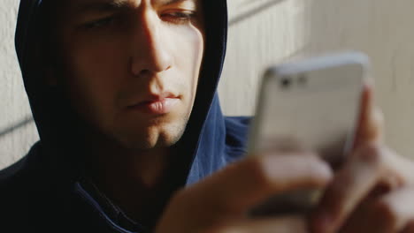 very tired man writes a message on the phone he's in the hood his eyes sleepy stick