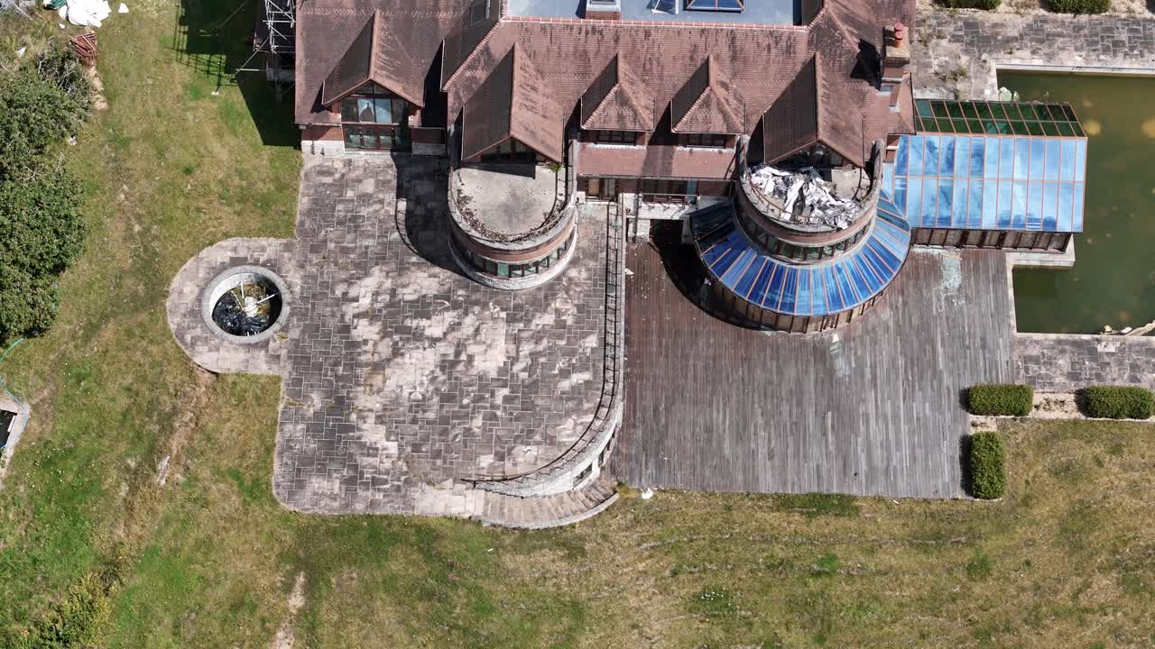 Aerial Birdseye view over rundown luxury celebrity mansion landscaped gardens and swimming pool