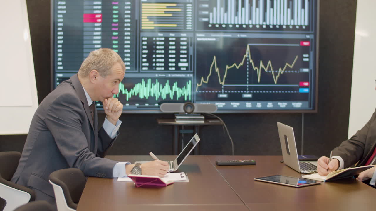 회의실에서 책상에 앉아 노트북을 사용하는 기업인