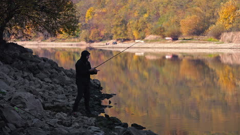 a fisherman enjoying an autumn day by the lake