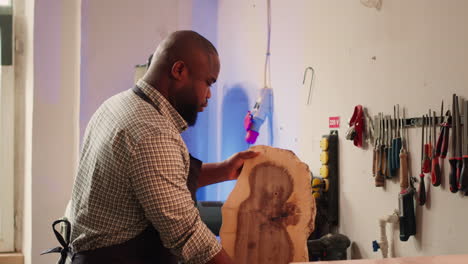 cabinetmaker in joinery studio evaluating lumber block, checking for damages