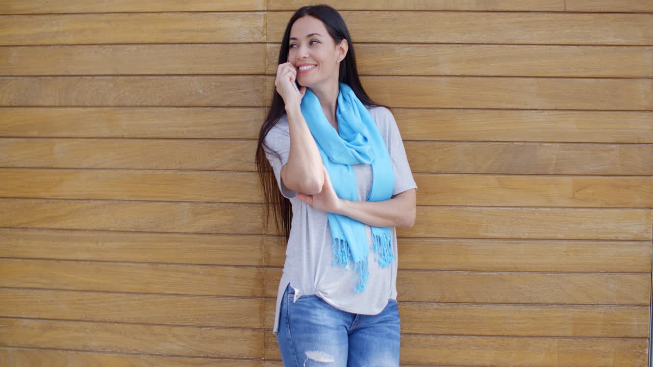 mujer al teléfono y apoyada contra la pared