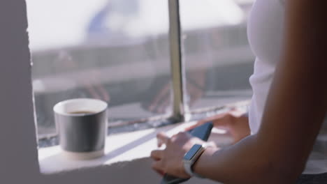 manos de una mujer joven usando un teléfono inteligente navegando mensajes disfrutando de mensajes de texto en el teléfono móvil en casa usando un reloj inteligente de cerca