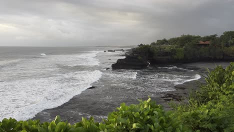 breaking waves on the rocky cliffs at the shore of tanah lot beach in bali, indonesia