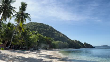 Stationary-view-of-the-ocean-rolling-against-the-shore-of-a-beautiful-white-sand-beach-on-a-tropical-island-in-Palawan,-the-Philippines