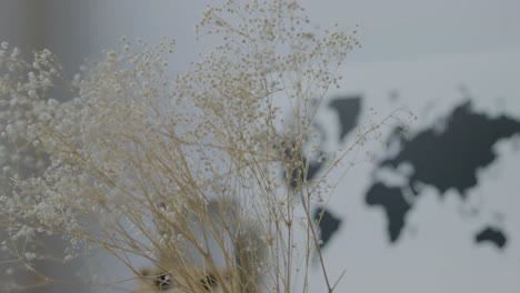 배경에 있는 테이블의 캔버스에 액자 세계 지도가 있는 말린 꽃