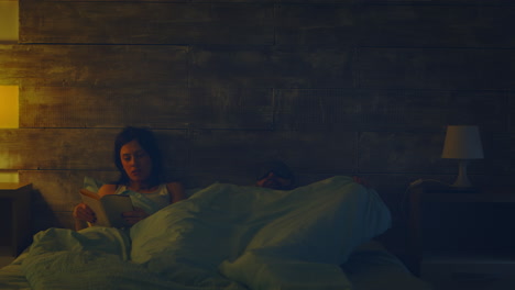 mujer leyendo un libro en la cama en la lámpara de la noche