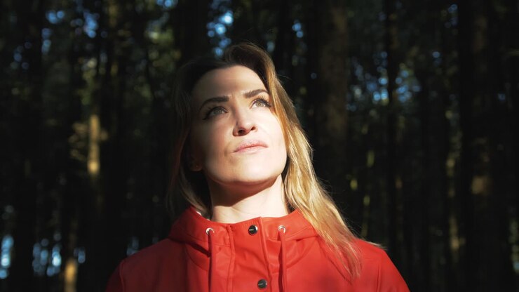 Mujer de pie bajo la hermosa luz solar del bosque, toma orbital