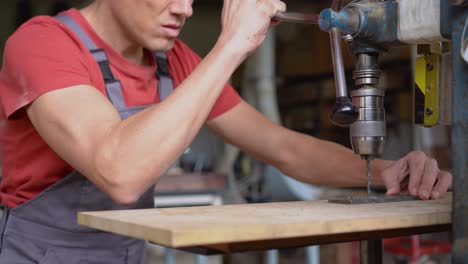 Man operating a drill press in a workshop
