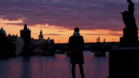 a silhouette figure gazing at the sunset over prague's charles bridge