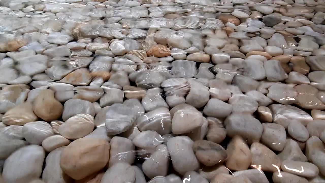 salpicaduras de agua, olas en la superficie del agua y piedras redondas en el fondo, estanque decorativo