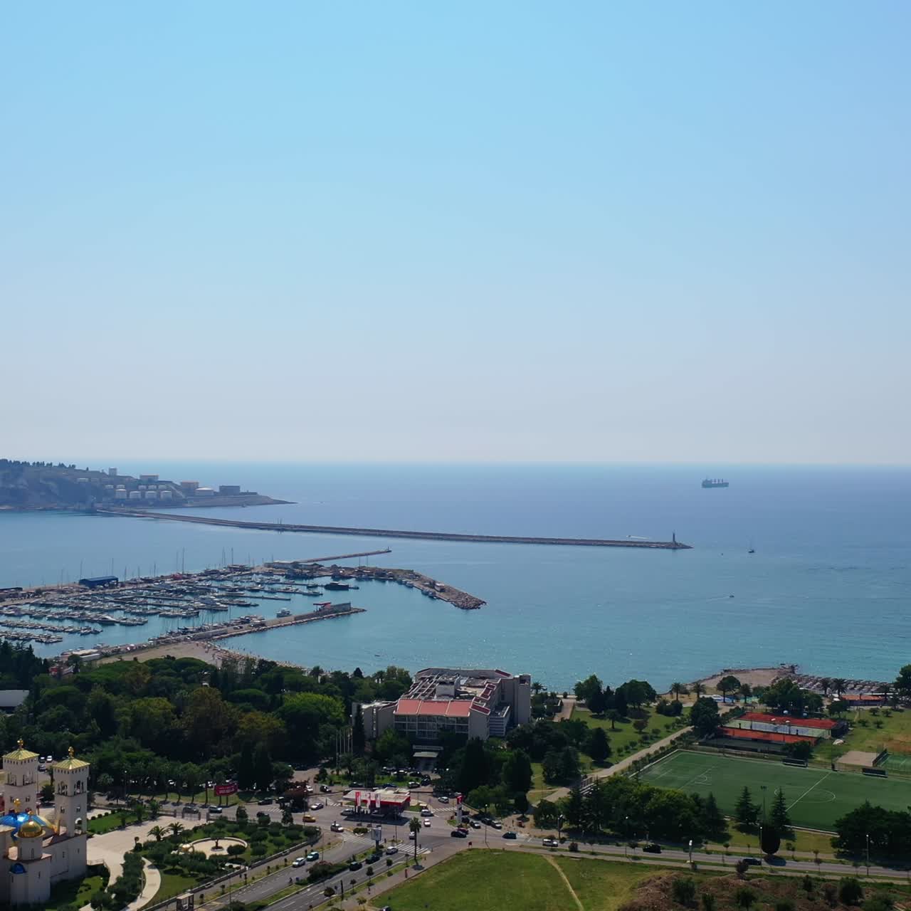 Busy seashore in the resort city of Bar, Montenegro. Beautiful cityscape and sea with yacht docks on sunny day. Top view