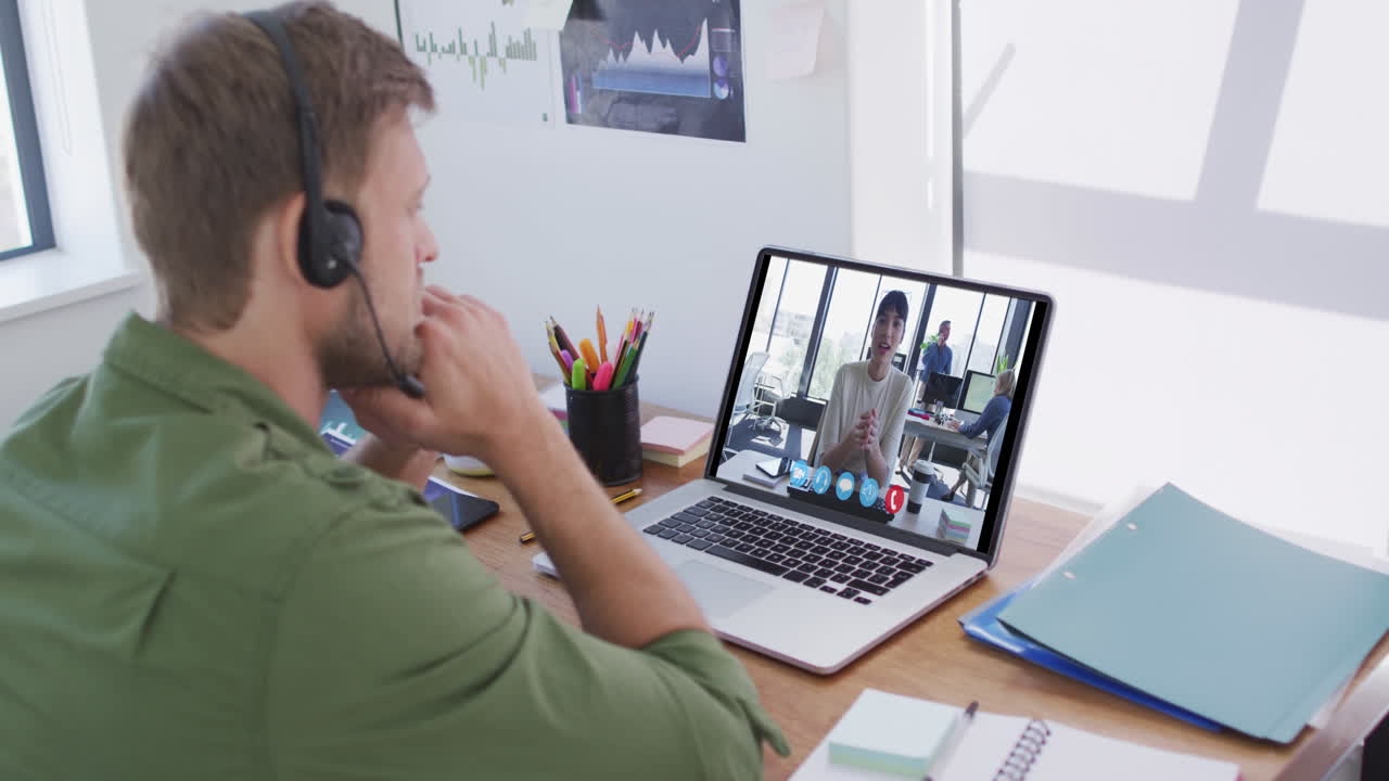 Kaukasisk mand bruger bærbar computer og telefonheadset på videoopkald med en kvindelig kollega.