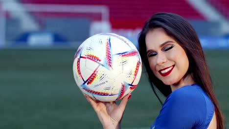 Brunette-in-football-jersey-plays-with-football-in-stadium