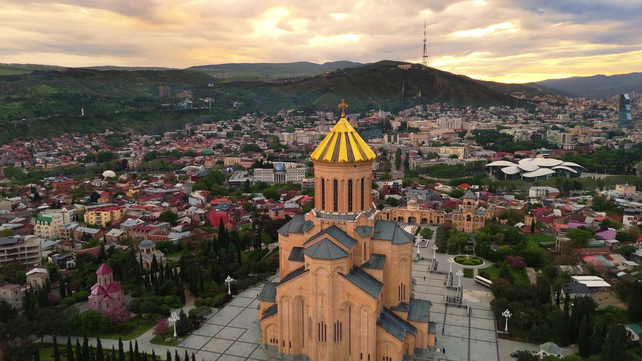 Letecký pohled na město Tbilisi, Gruzie při západu slunce, dron odhaluje zlatou kupoli a horní architekturu katedrály Nejsvětější Trojice (Sameba)