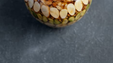 parte de un frasco con nueces en miel en la mesa negra.