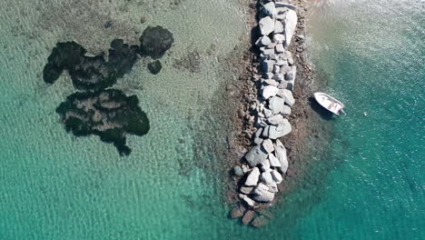 Anclas-De-Barco-En-Un-Muelle-Rocoso-En-Agua-Turquesa,-Toma-De-Pedestal-Aéreo