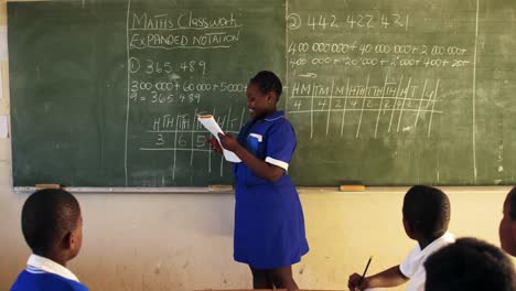 young schoolgirl standing at the blackboard in class 4k